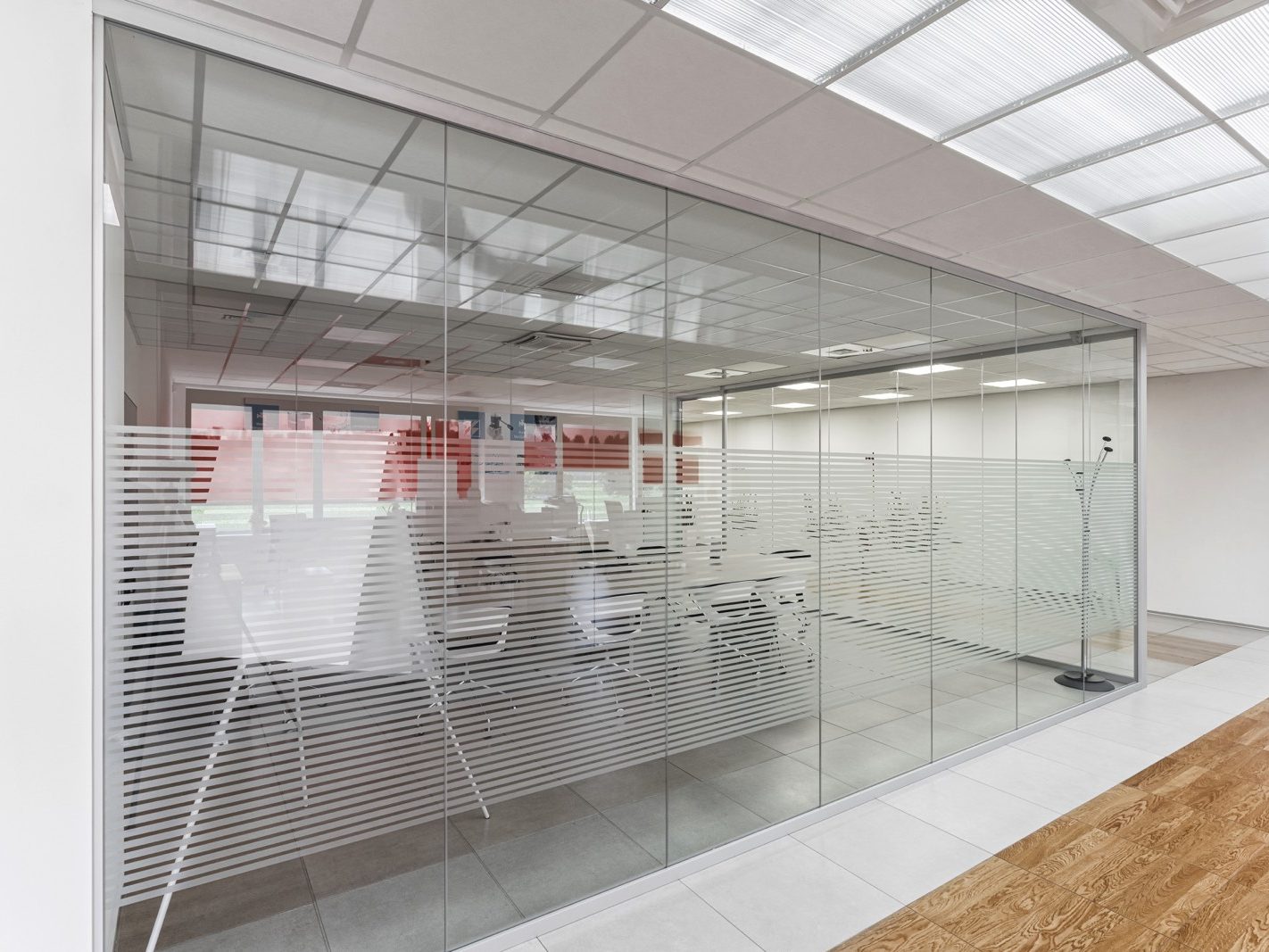 Sala Conferenze. Una sala conferenze con pareti di vetro decorate con pellicole opache a righe orizzontali, che garantiscono un equilibrio tra privacy e apertura. La luce naturale filtra attraverso le pareti, illuminando l'intero spazio.