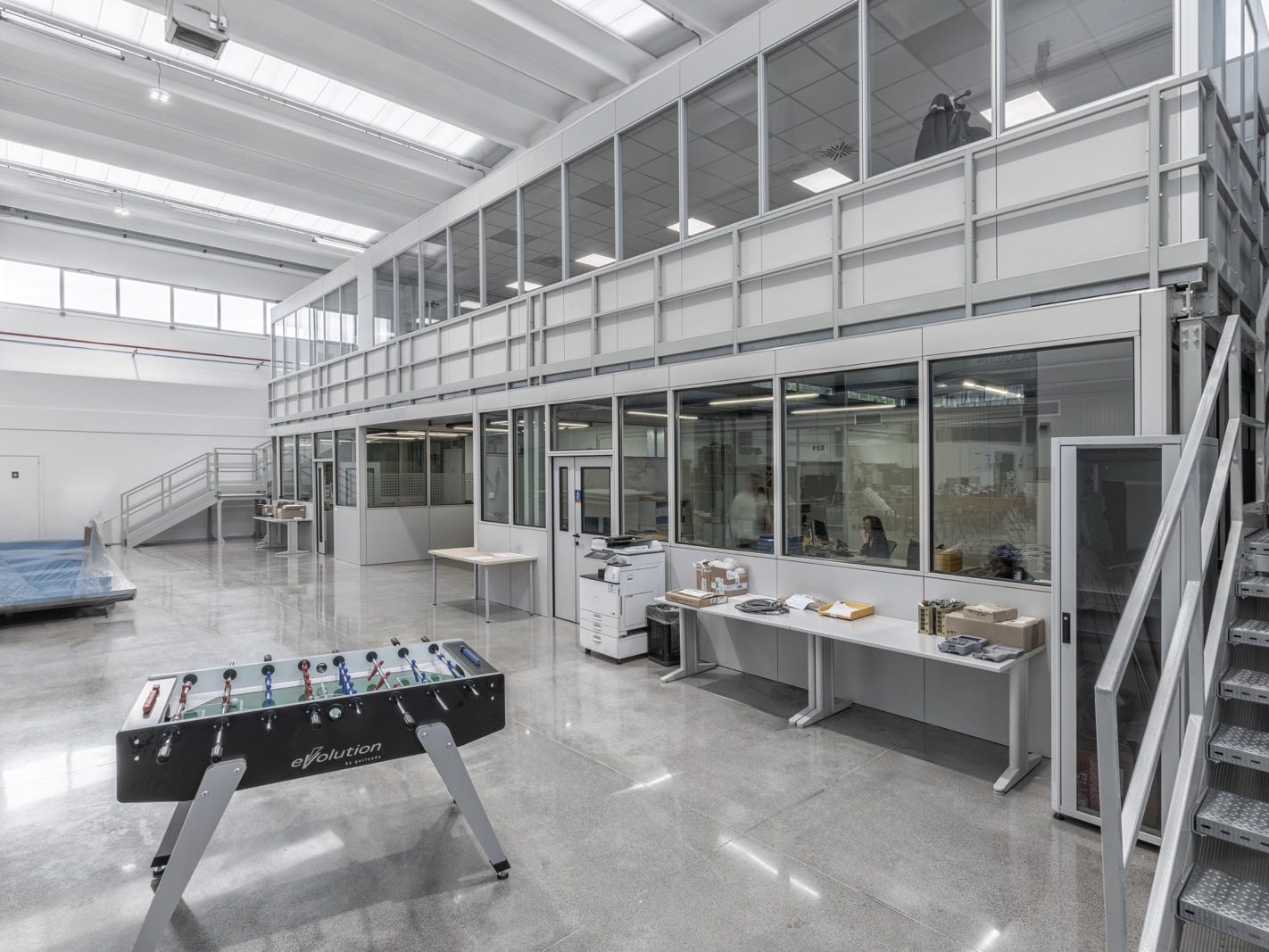 Le pareti divisorie modulari in vetro creano un ambiente aperto e luminoso. Una scala in metallo che conduce al piano superiore.